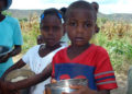 A Haitian boy and girl stand with bowls of rice Más de 100,000 niños expuestos a la “desnutrición aguda” en Haití