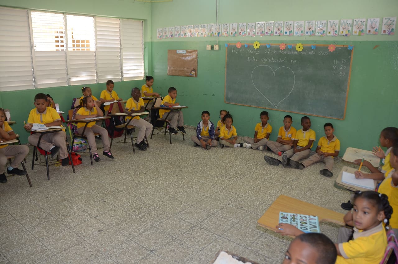 un grupo de ninos sentados en una mesa 06c72bb2 Eso No Es Nuevo: Hay estudiantes que tienen que sentarse a recibir el pan de la enseñanza en el suelo